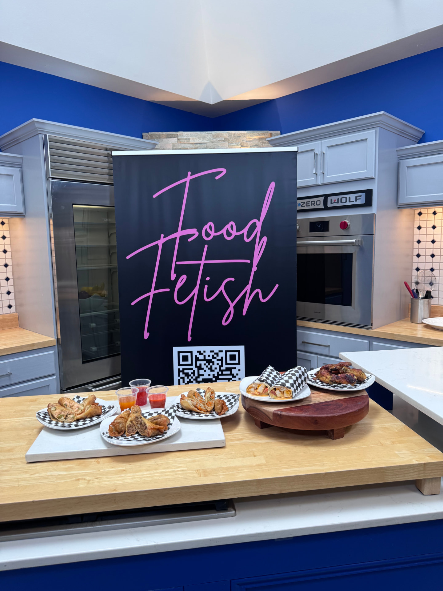 Food Fetish branded banner standing in a demonstration kitchen behind plates of prepared food