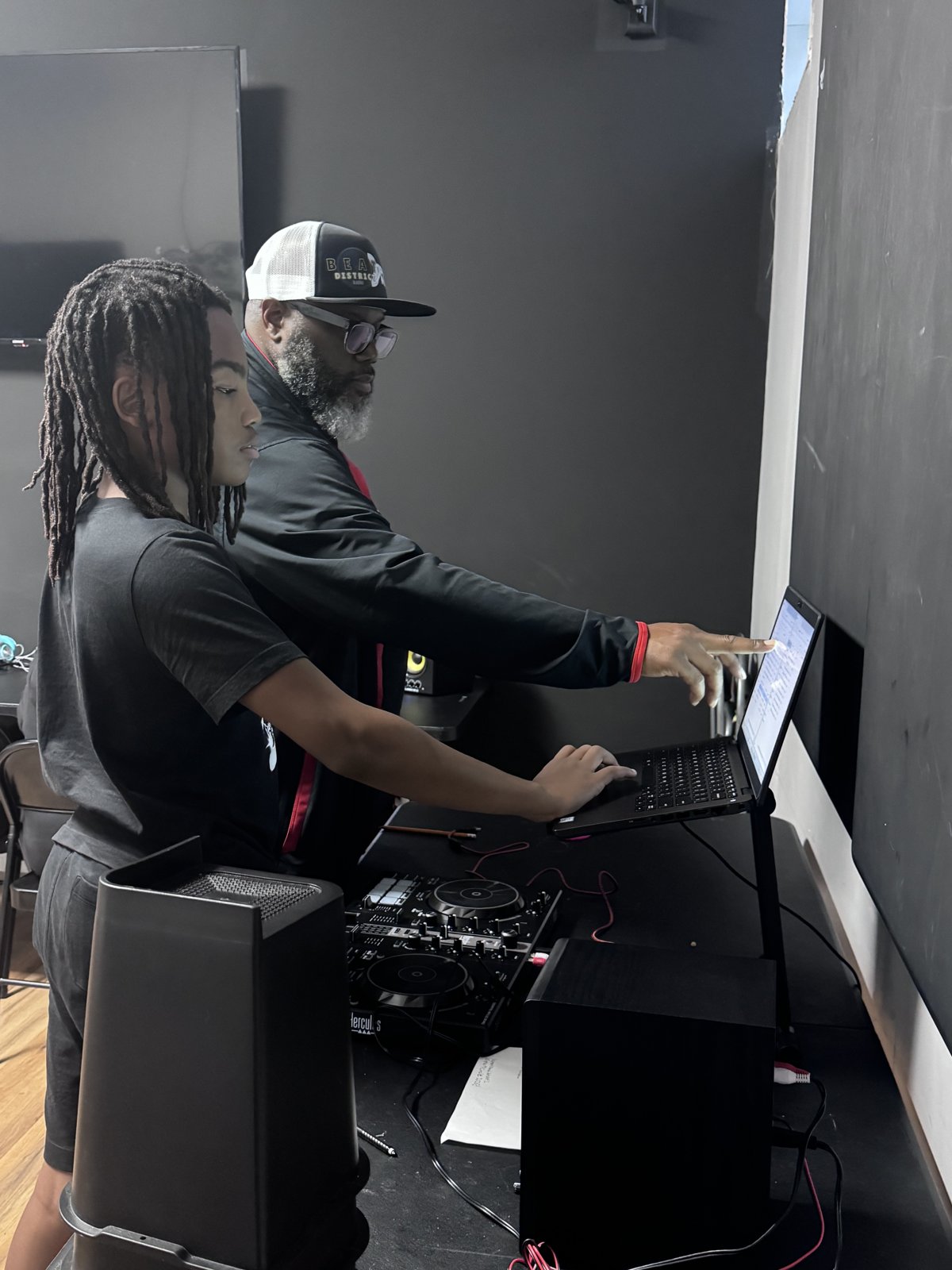 New Avenue mentor guiding a young DJ at the turntables and laptop